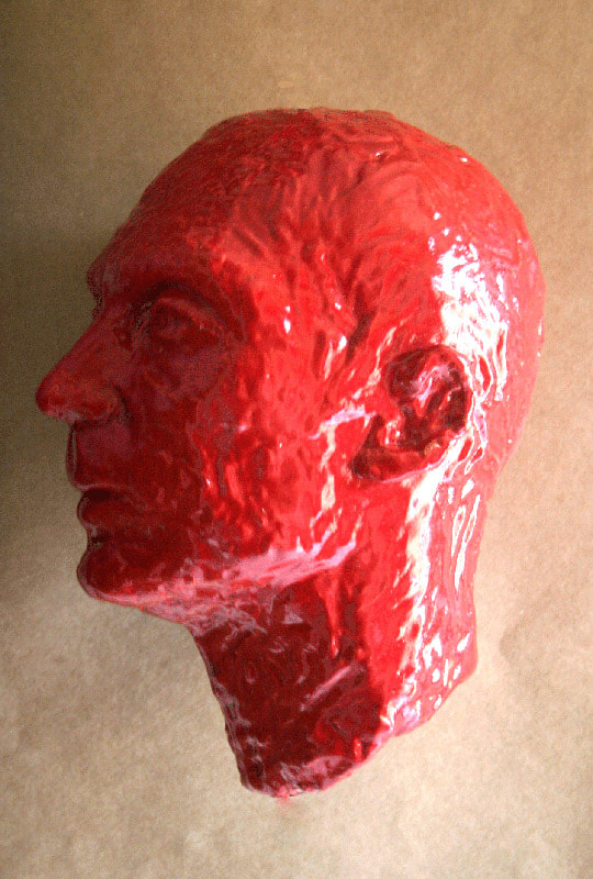 Sculpture of the head of a man in red colour made of  glazed ceramic